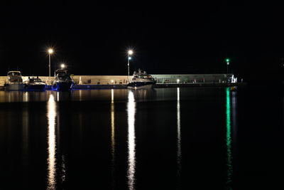 Illuminated boats in sea against sky at night