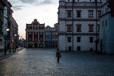 Rear view of man standing against buildings in city