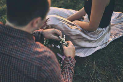 Midsection of friends sitting on field