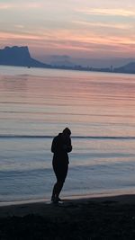 Silhouette man on beach against sky during sunset