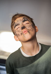 Low angle view of boy with face paint standing at home