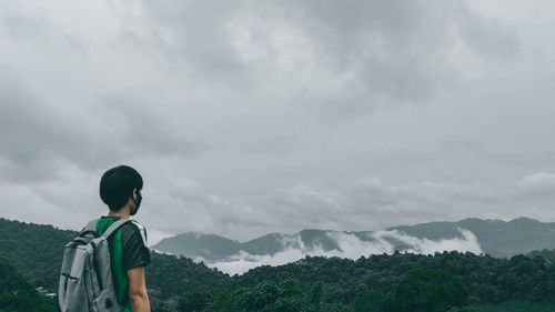 Rear view of man standing against mountain and sky