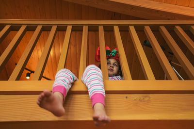 Low angle view of girl sitting at wooden railing during christmas