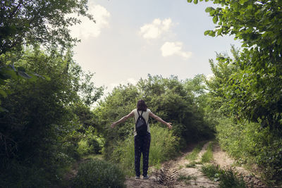 Man standing amidst plants and trees against sky