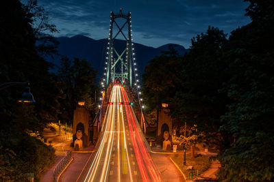 Light trails on road against sky at night