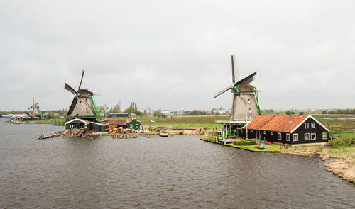 Traditional windmill by water against sky