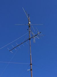 Low angle view of electricity pylon against blue sky