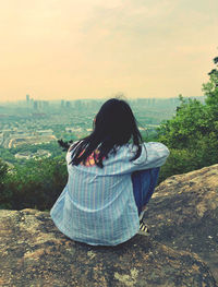 Rear view of woman looking at cityscape against sky