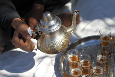 Cropped image of man hand pouring mint tea in glass