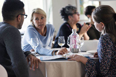 Mother talking to daughter and man with magazine at dinner party