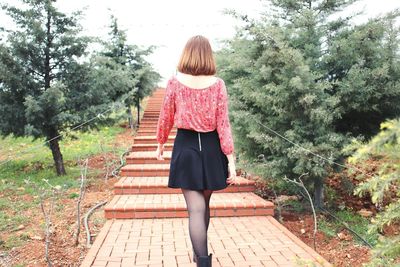 Rear view of young woman moving up on steps at park