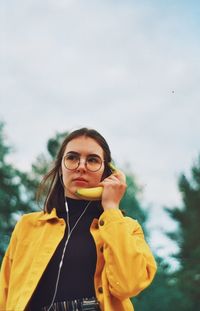 Portrait of young woman standing against yellow sky