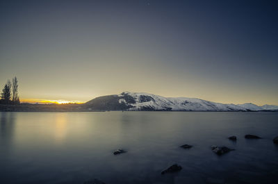 Scenic view of lake against clear sky during sunset