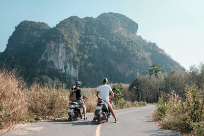 Rear view of people riding bicycle on road