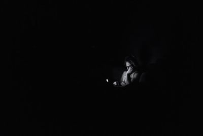 Low angle view of girl sitting against black background