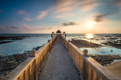 A long exposure picture of golden sunrise with stone jetty