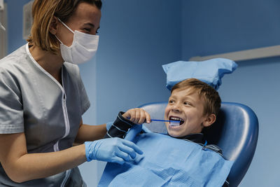 Cheerful boy brushing teeth by dentist in medical clinic