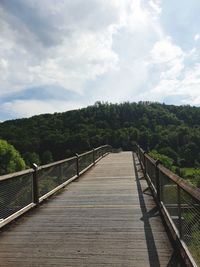 Footbridge over stream against sky