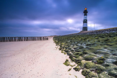 Lighthouse by sea against sky