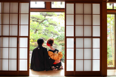 Rear view of people sitting in window