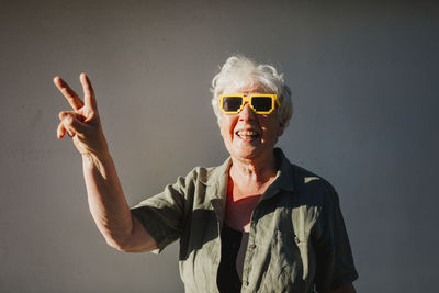 Smiling senior woman showing peace sign