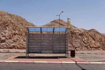 Bus stop by mountains against clear sky