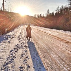 Rear view of person walking on snow covered landscape