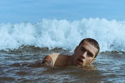 Young man swimming in splashing sea