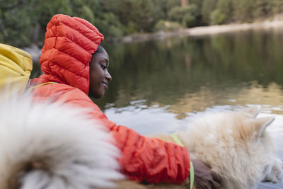 Smiling young woman with dog in front of lake