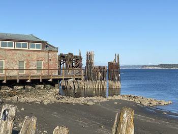 Abandoned building by sea against clear blue sky