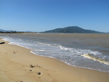 Scenic view of sea and mountains against clear blue sky