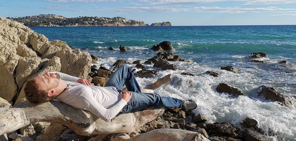 Man relaxing on rocks at beach