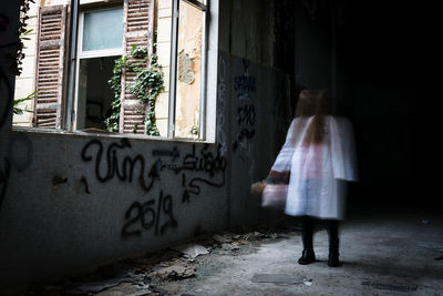 Rear view of woman walking by building