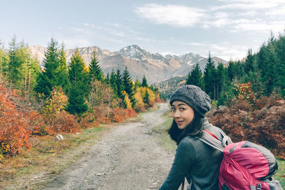 Portrait of woman standing on road in forest during autumn