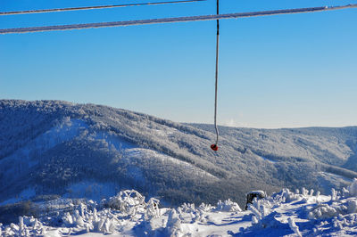 Overhead cable car on snowcapped mountains against sky