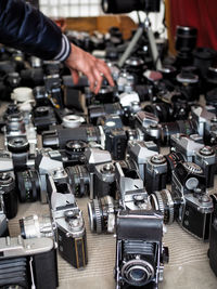 Cropped image of hand touching cameras for sale in flea market