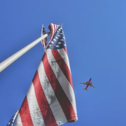 Low angle view of american flag against clear blue sky during sunny day