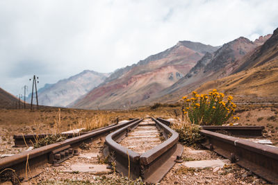 Railroad track by mountains against sky