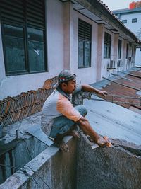 Young man sitting outside house