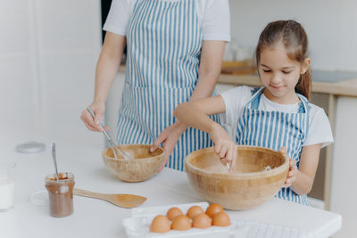 Midsection of woman making food while standing by girl