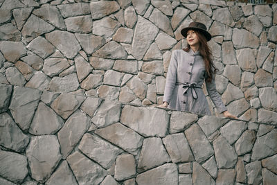 Full length of woman standing against brick wall