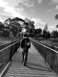 Rear view of woman walking on footbridge