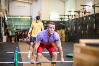 Muscular guy lifting barbell in modern gym