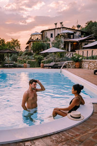 Rear view of couple in swimming pool against sky