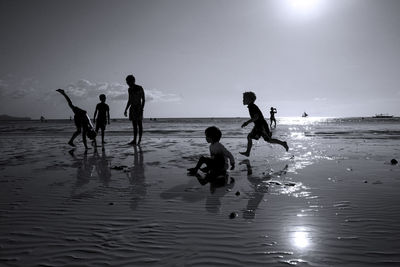 People playing on beach against sky