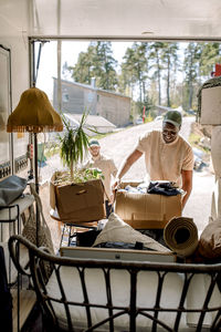 Multiracial delivery men picking cardboard boxes from truck