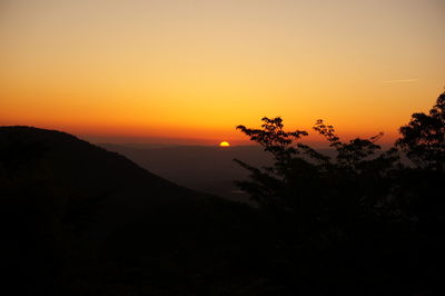 Scenic view of silhouette landscape against orange sky