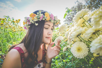 Beautiful woman wearing flowers by plants
