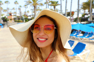 Portrait of smiling young woman wearing sunglasses at swimming pool