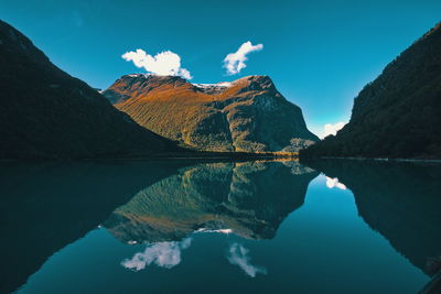 Scenic view of lake and mountains against blue sky